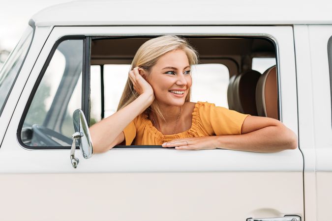 Woman resting head on hand leaning out of vehicle window