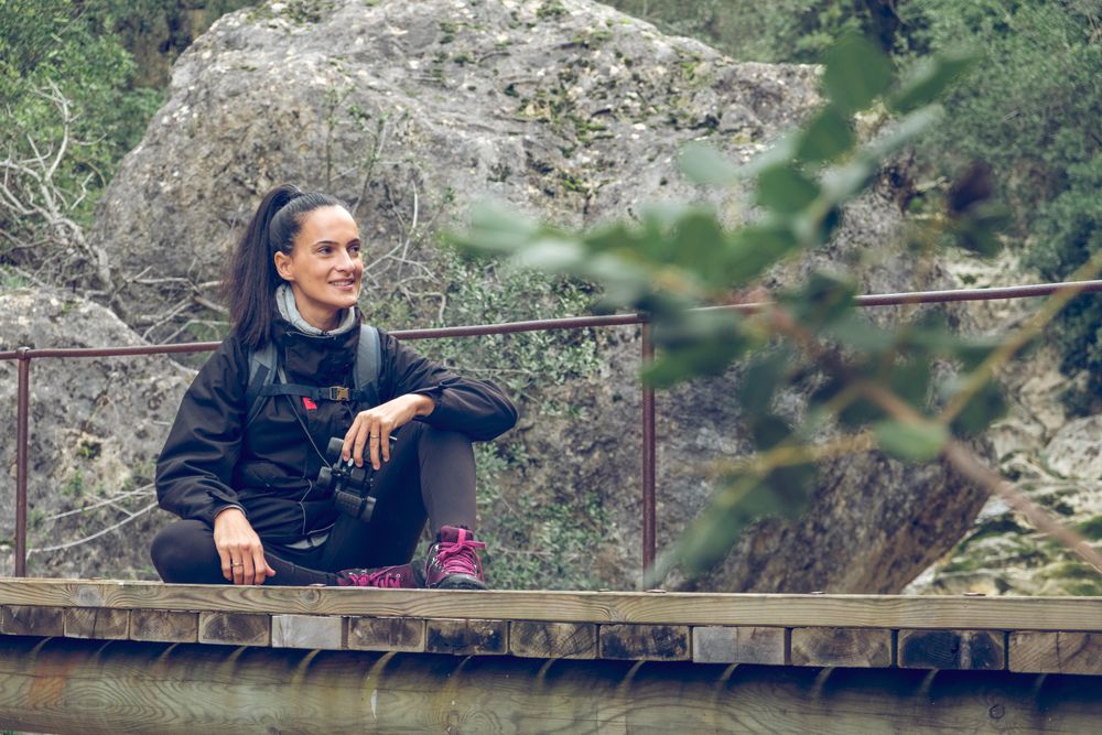 Happy female hiker relaxing on bridge during trekking in