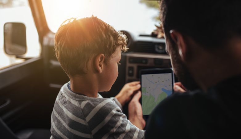 Man with little boy using navigation app on digital tablet