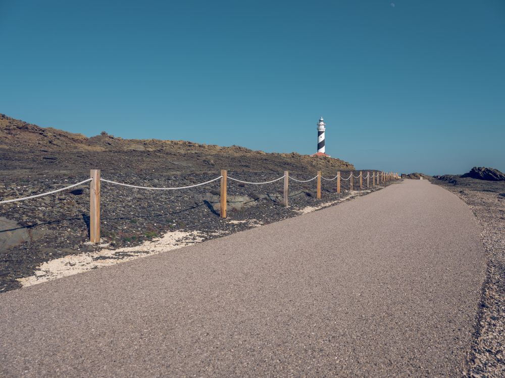 Lighthouse on top of hill and asphalt road