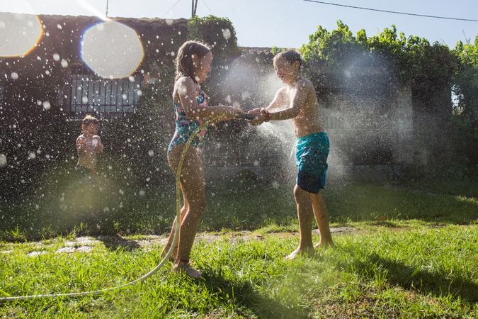 Little kids in swimwear having fun with splashing water