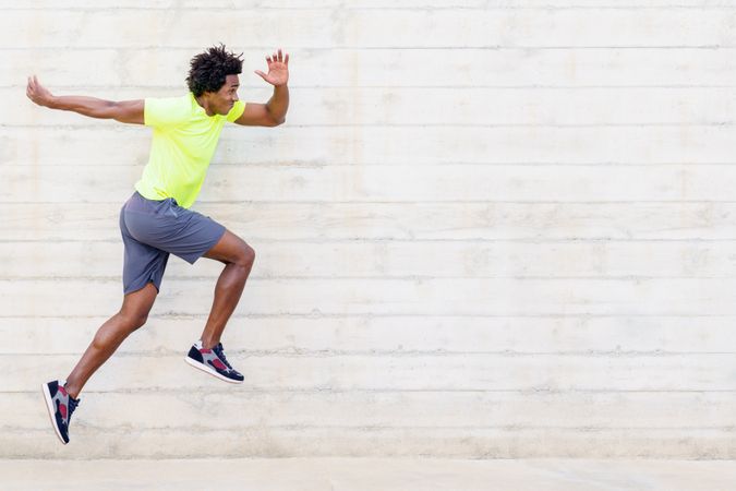 Side view of man doing running jumps in neon shirt