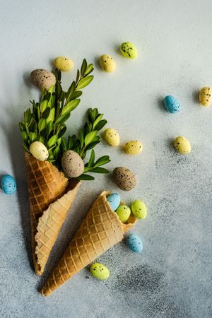 Easter card concept with green branch in waffle cone with pastel eggs