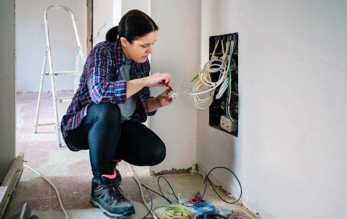 Technician with screwdriver and terminal strip installing telecommunication box