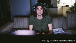 Young man wearing headphones and holding game controller while playing video game 4Z6Kr4