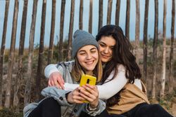 Young woman embracing girlfriend while resting together on boardwalk in nature