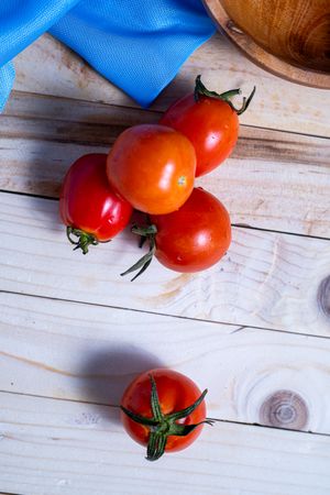 A bunch of red tomatoes are on a wooden table
