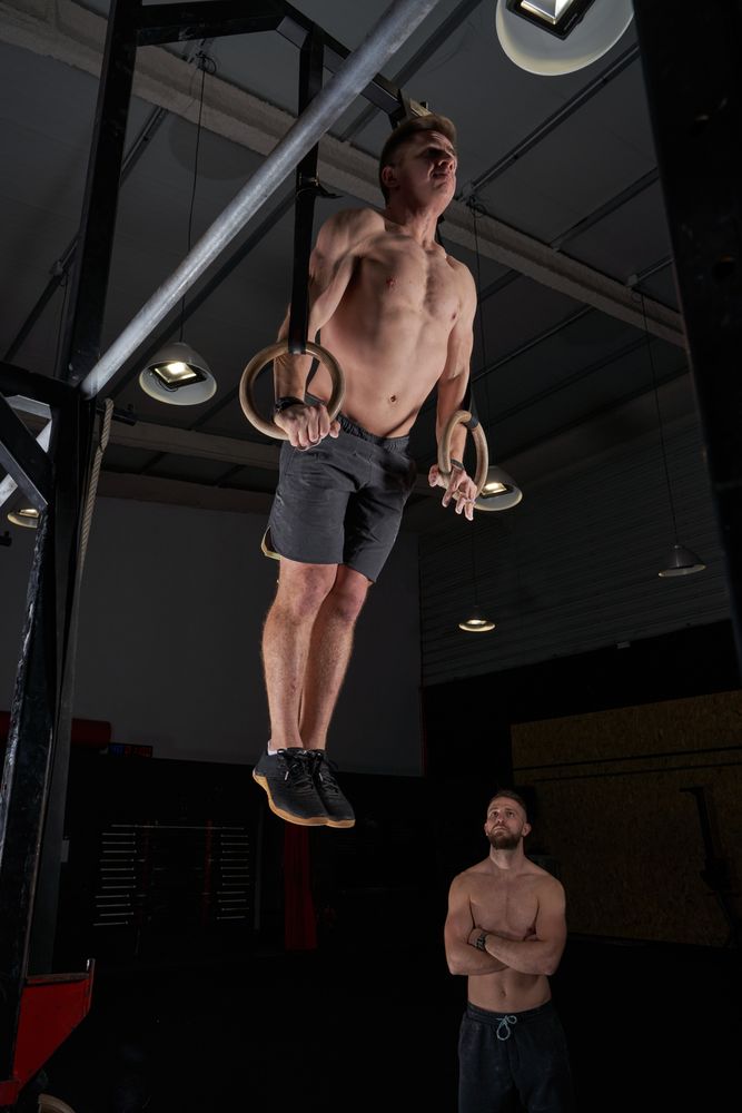 Sportsmen in gym during exercises on gymnastic rings
