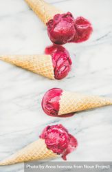 Four cones of dark berry ice cream on marble slab 5rPrnb