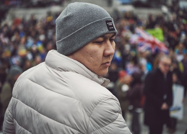 London, England, United Kingdom - March 5 2022: Asian man in grey hat and coat in crowd