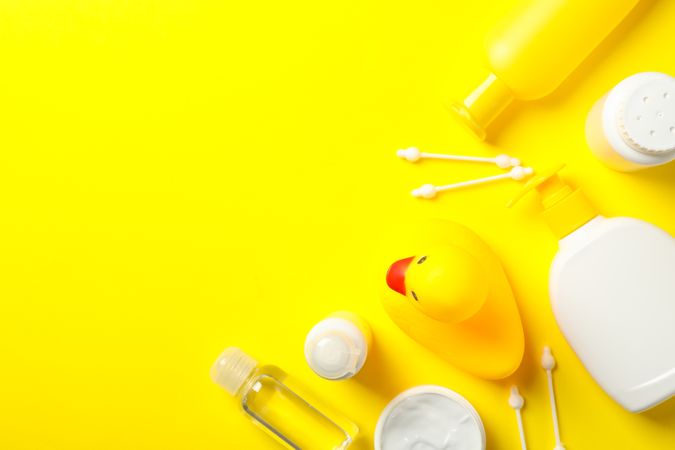 Baby hygiene accessories on yellow background, top view and space for text