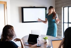 Woman CEO leading meeting in conference room with blank presentation screen behind