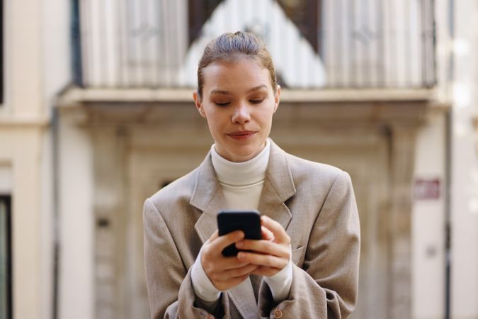 In a busy city, a young woman is focused on her smartphone, immersed in her digital world