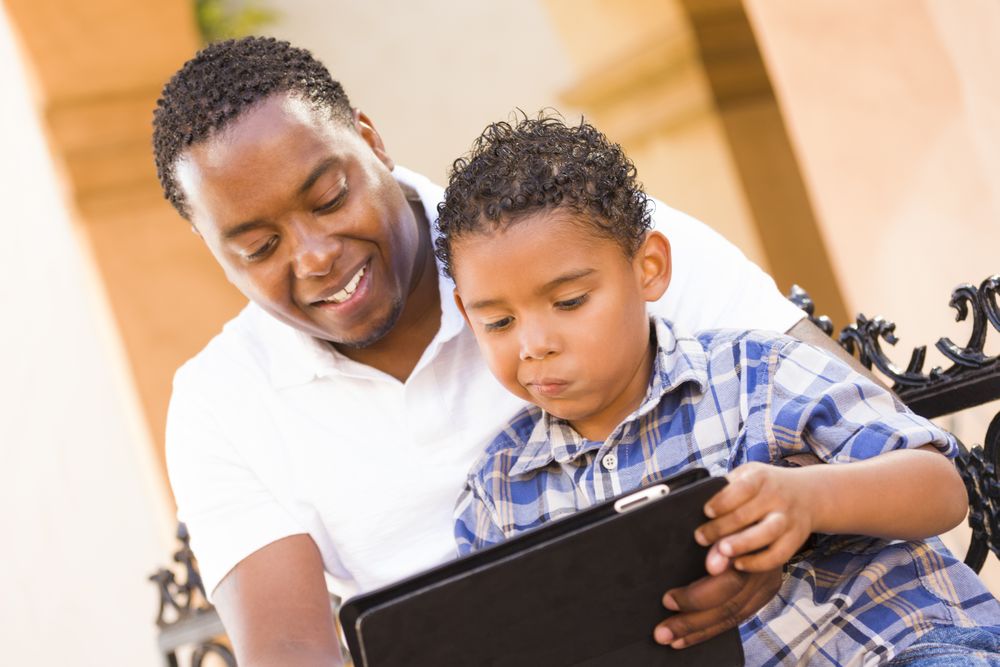 Black Father and Son Using Tablet On Balcony