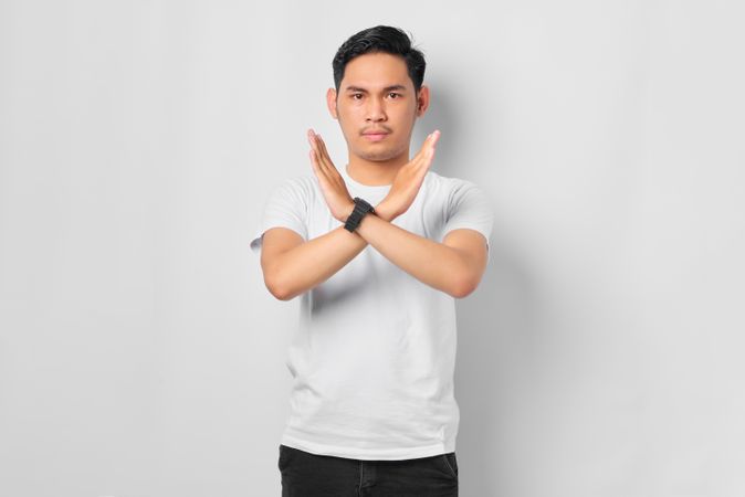 Asian male in grey studio with arms crossed in “x”
