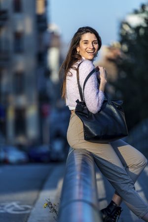 Woman in casual wear sitting on bridge on a sunny day