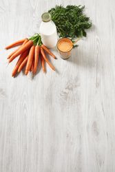 Top view of carrot juice with bunch of carrots and bottle of milk with copy space