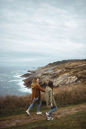 Happy female friends walking on trail at seaside