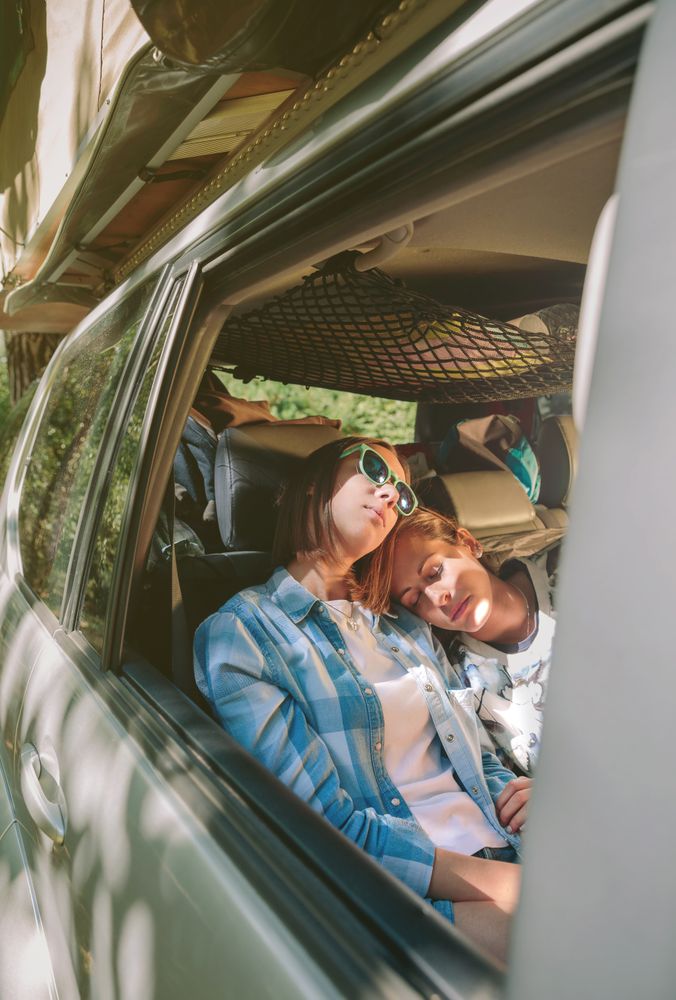 Tired women friends sleeping inside of car
