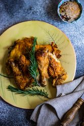 Grilled chicken with rosemary on yellow plate with napkin and rosemary