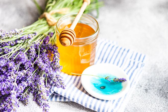 Honey jar on napkin with dipper and bunch of lavender