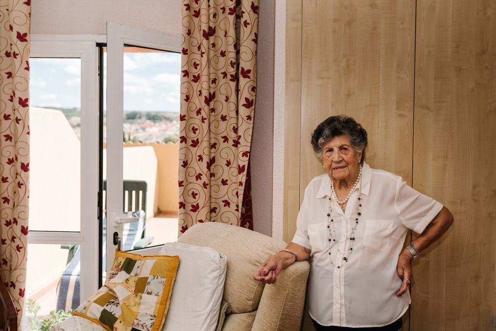 Older woman standing near armchair at home