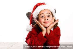 Female child in santa outfit lying on stomach on ground resting her head on her hands 4mJOXb