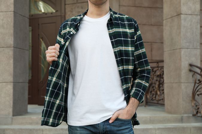 Men in t-shirt and checkered shirt against building, copy space