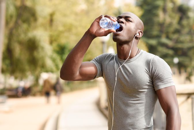 Athletic male drinking from a water bottle in an outdoor park