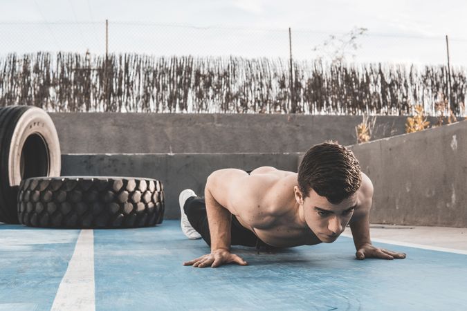 Shirtless male performing push ups on street