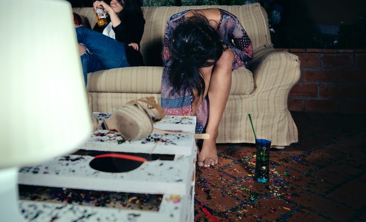 Young inebriated woman sitting on the sofa on a party with her head in her lap