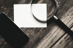 Piece of paper, cell phone magnifying glass on wooden table
