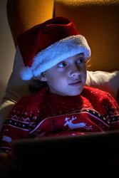 Little boy in Christmas hat sitting in armchair