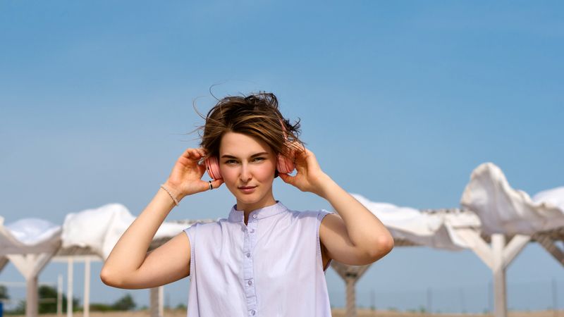Woman listens to music with headphones outdoors