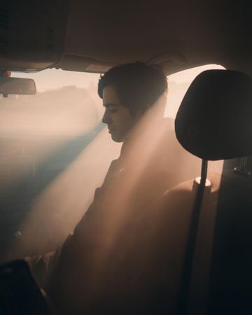 Man sitting in the front seat of car during golden hours