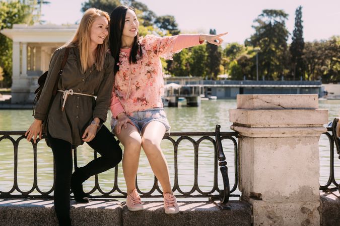 Cheerful multiracial friends sitting on embankment