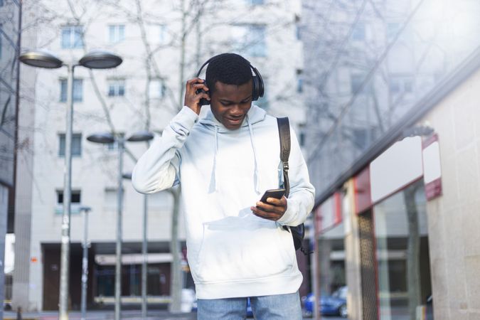 Young Black man standing in the street listening to music on headphones