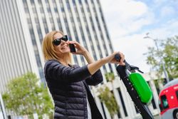 Woman speaking on smartphone and riding electric scooter