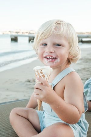 Happy boy eating ice cream on beach