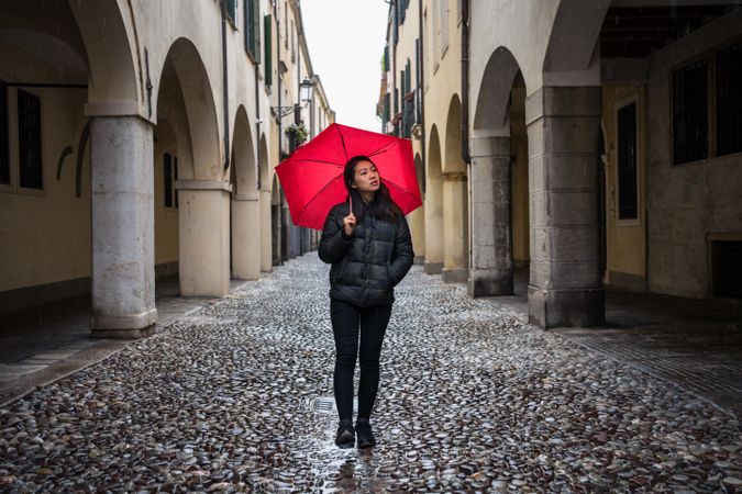 Asian female tourist with umbrella walking at city street on rainy weather