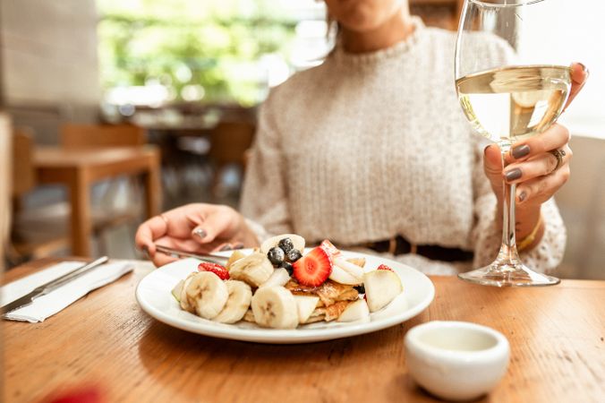 Woman in gray sweater drinking wine and having a dessert