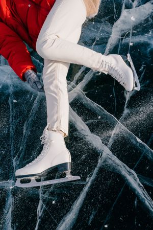Happy woman in skates lying on ice