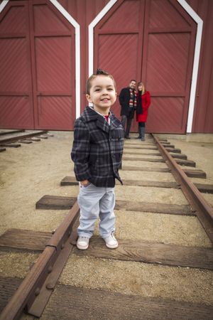 Boy at Train Depot with Parents Smiling Behind