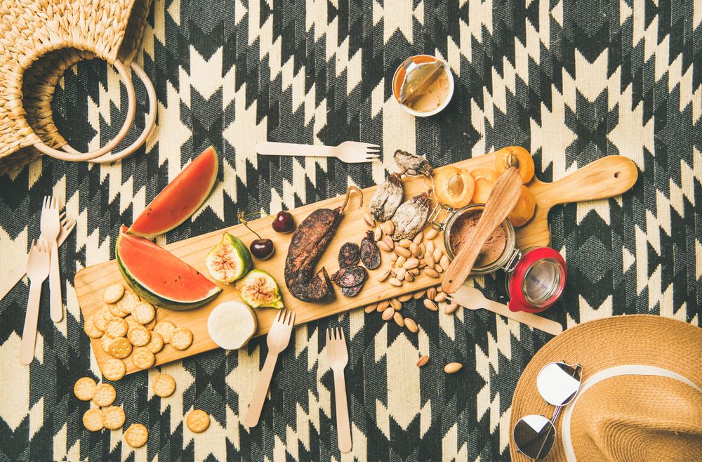 Summer picnic on pueblo pattern blanket, with board of pate, meats, and fruit