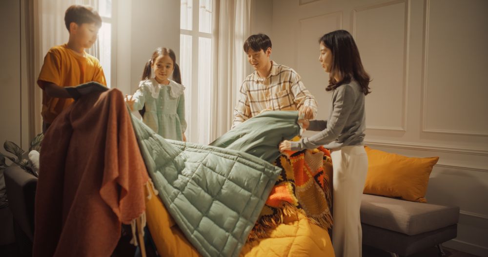 Happy Korean Family Spending Quality Time Together at Home: Young Parents Building a Fortress out of Blankets for their Adorable Children, Kids Helping Out.