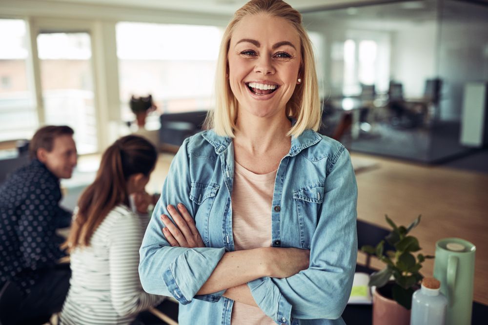 Portrait of blonde business woman smiling in an office with her arms crossed