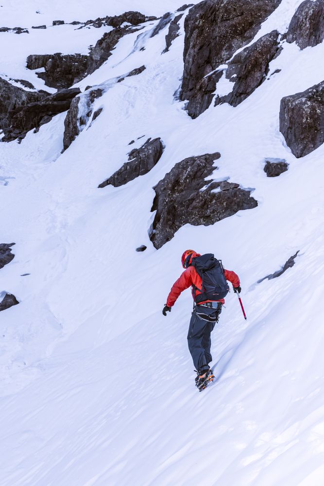 Tourist walking at snowy mountain slope