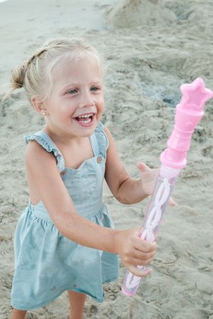 Delighted adorable girl with soap bubbles smiling and playing on