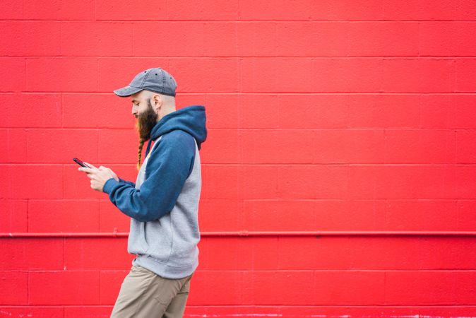 Man using smartphone near red wall