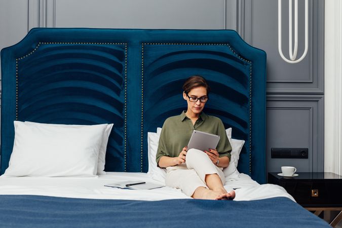 Woman in glasses working from her hotel suite with a tablet